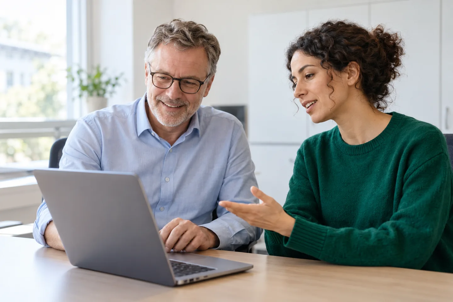 Consultant explaining the setup to the school secretary on a laptop