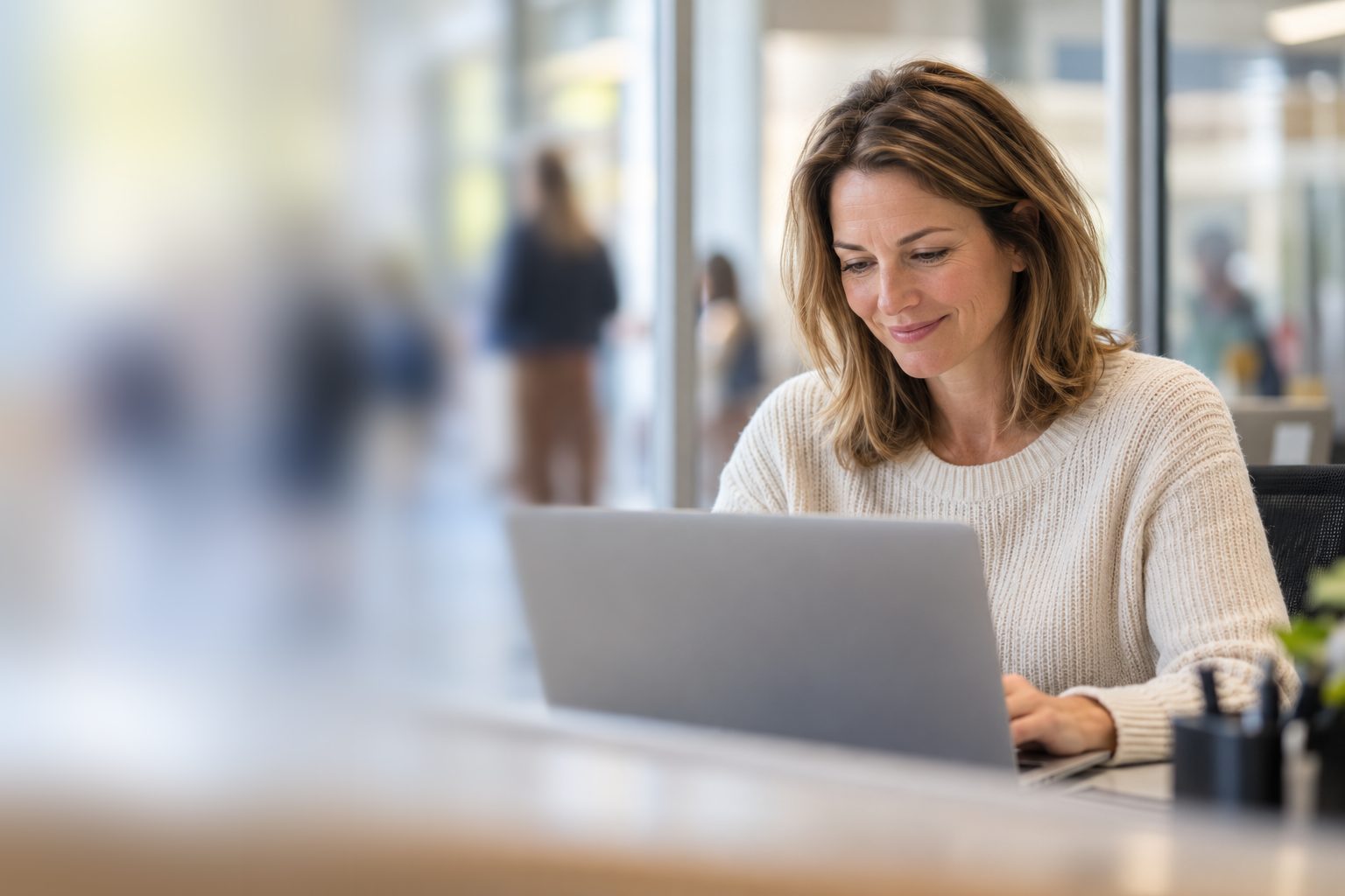 A school office employee smiling at her laptop